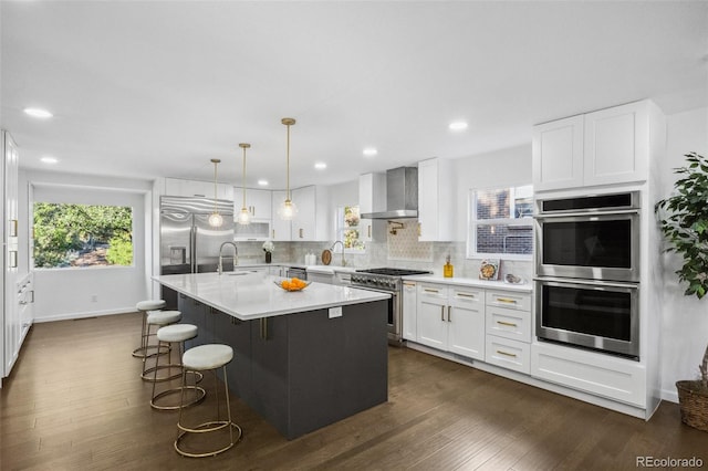 kitchen featuring wall chimney exhaust hood, white cabinetry, high quality appliances, and dark wood-type flooring