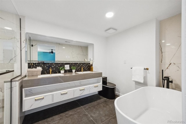 bathroom featuring vanity, tile patterned floors, a tub, and tasteful backsplash