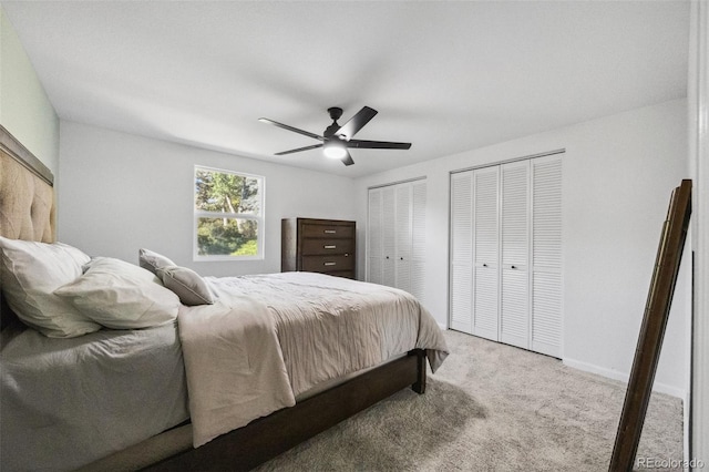 bedroom with light carpet, two closets, and ceiling fan