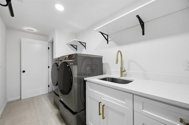 laundry area with sink, washing machine and dryer, and cabinets