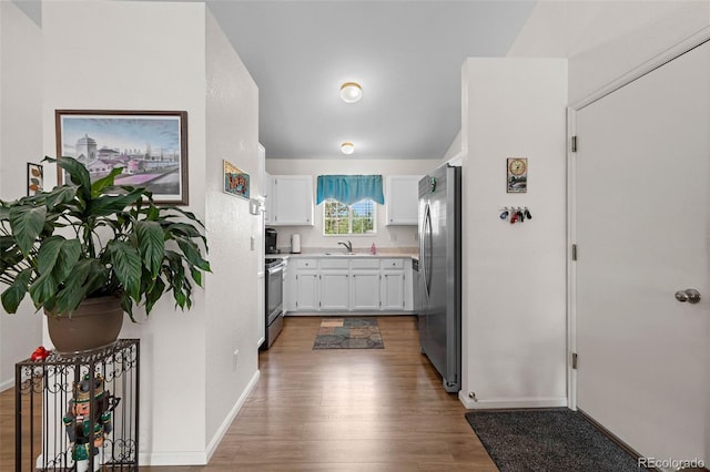 4421 Sunshine Cir, Loveland, CO 80538 - kitchen featuring stainless steel appliances, wood finished floors, a sink, white cabinetry, and light countertops
