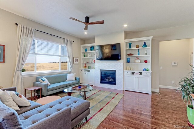 living room with ceiling fan, wood-type flooring, and a fireplace