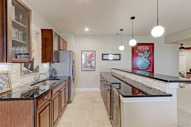 kitchen featuring backsplash, sink, ceiling fan, hanging light fixtures, and a breakfast bar