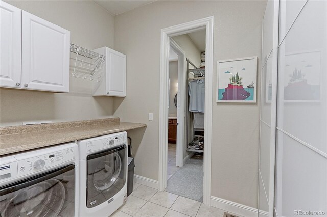 clothes washing area featuring light tile patterned flooring, cabinets, and washer and dryer