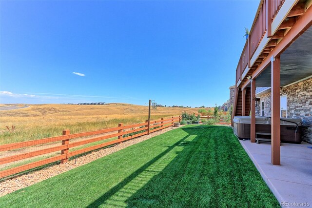 view of yard featuring a hot tub, a rural view, and a patio