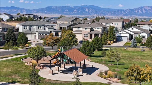 view of community with a mountain view, a garage, a playground, and a lawn