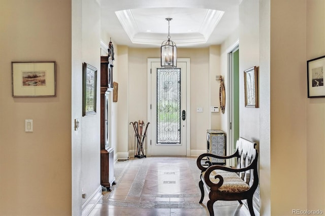 foyer with a raised ceiling and ornamental molding