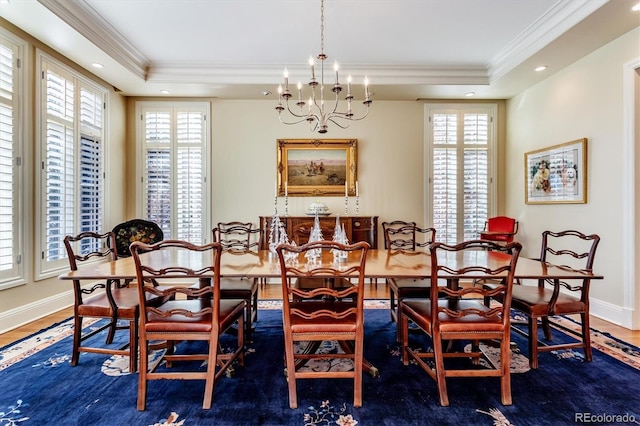 dining space with a raised ceiling, crown molding, and a chandelier