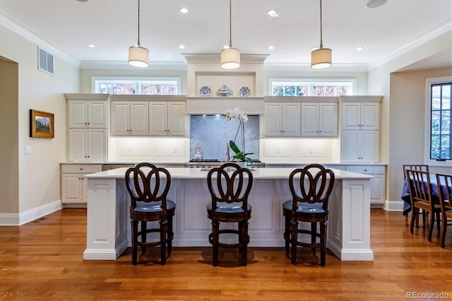 kitchen with a large island with sink, pendant lighting, and a kitchen bar