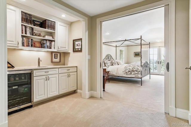 carpeted bedroom with french doors and beverage cooler