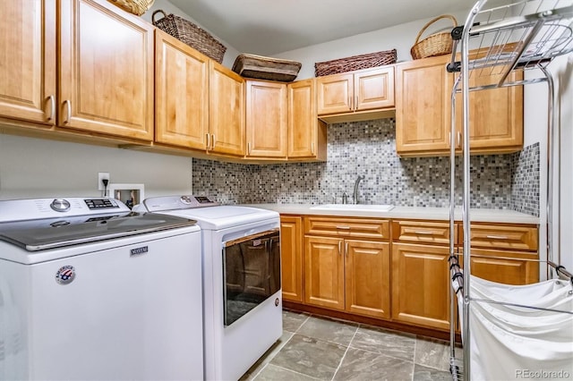 clothes washing area with cabinets, sink, and washing machine and clothes dryer