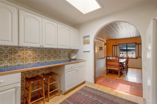 2309 E Floyd Pl, Englewood, CO 80113 - kitchen with arched walkways, light wood-type flooring, and white cabinets