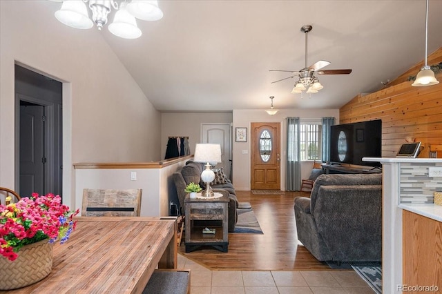 1176 E Purcell Ln, Pueblo, CO 81007 - living room featuring vaulted ceiling, a ceiling fan, tile patterned flooring, wooden walls, and a chandelier