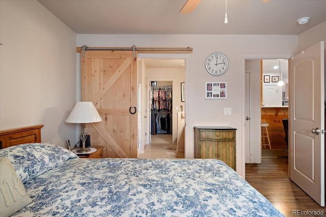 1176 E Purcell Ln, Pueblo, CO 81007 - bedroom featuring a walk in closet, wood finished floors, a barn door, a closet, and ceiling fan
