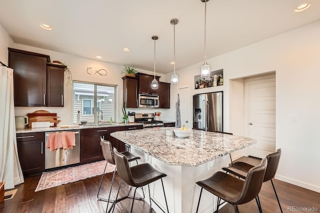 2592 Sweet Wind Ave, Castle Rock, CO 80109 - kitchen with stainless steel appliances, dark brown cabinets, a breakfast bar area, a kitchen island, and recessed lighting