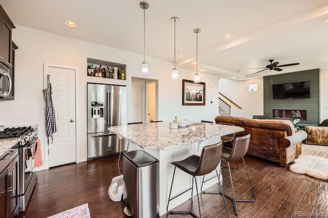 2592 Sweet Wind Ave, Castle Rock, CO 80109 - kitchen with stainless steel appliances, dark wood finished floors, a breakfast bar area, a kitchen island, and open floor plan