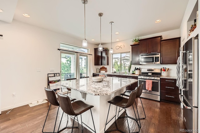 2592 Sweet Wind Ave, Castle Rock, CO 80109 - kitchen featuring stainless steel appliances, dark brown cabinetry, dark wood finished floors, a kitchen bar, and recessed lighting