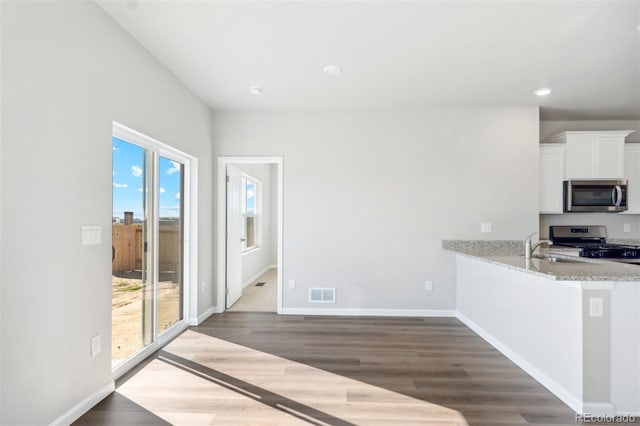 kitchen featuring light stone countertops, white cabinetry, sink, stainless steel appliances, and dark hardwood / wood-style floors