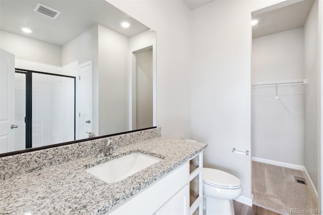 bathroom with hardwood / wood-style flooring, vanity, toilet, and a shower with shower door