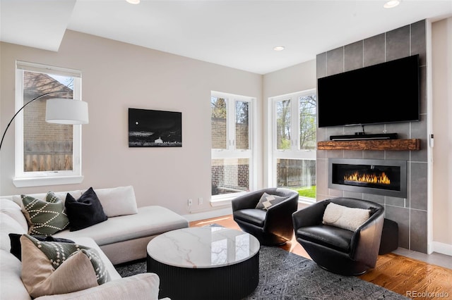 living room featuring wood finished floors, recessed lighting, a tiled fireplace, and baseboards