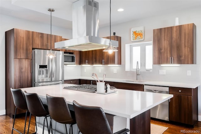 kitchen featuring appliances with stainless steel finishes, a sink, island range hood, light countertops, and recessed lighting