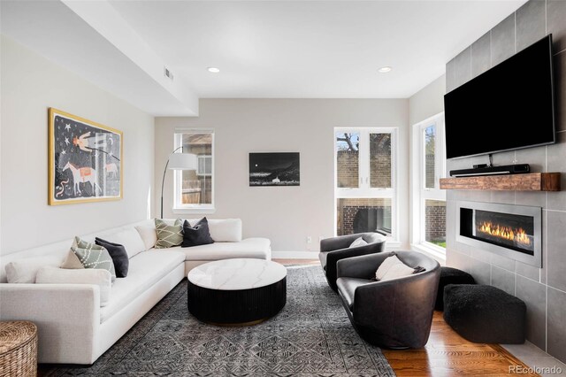 living area with a tiled fireplace, wood finished floors, and recessed lighting