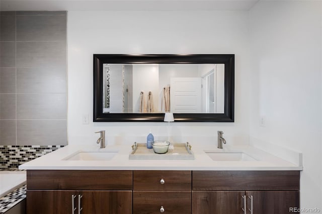 bathroom featuring double vanity, backsplash, and a tub to relax in