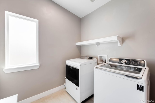 clothes washing area with independent washer and dryer, baseboards, and light tile patterned floors
