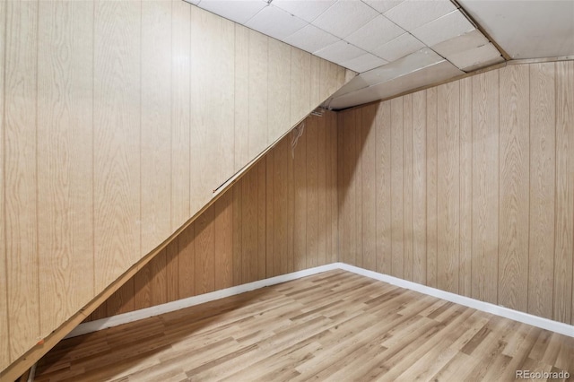 basement with wooden walls and light wood-type flooring