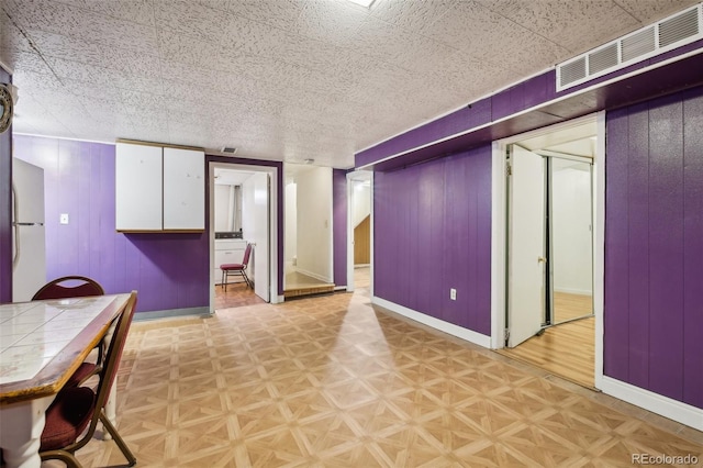 basement with wood walls and light parquet floors