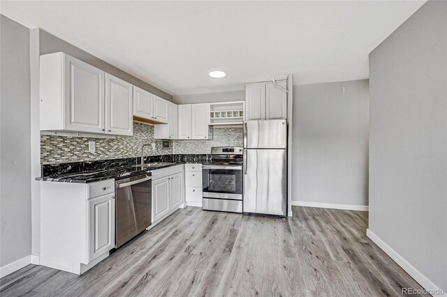 kitchen featuring light wood-type flooring, white cabinets, backsplash, stainless steel appliances, and sink