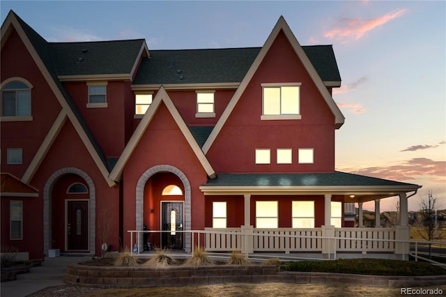 view of front facade with covered porch, stucco siding, and a shingled roof