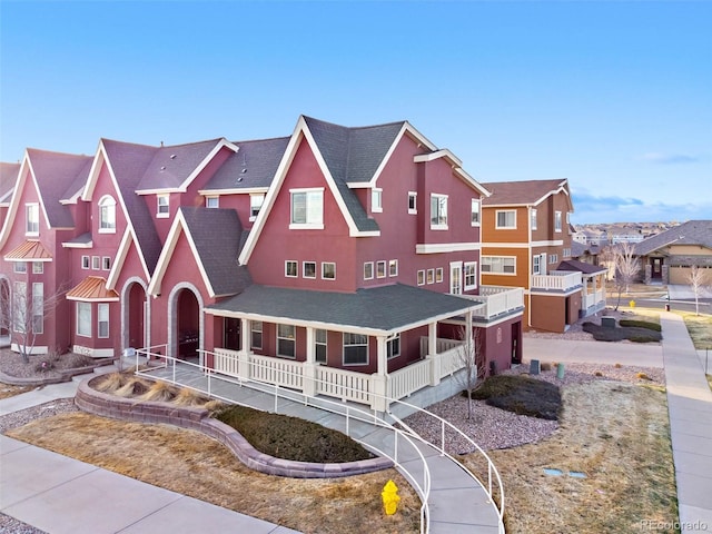 view of front of property featuring stucco siding, a porch, a residential view, roof with shingles, and a garage