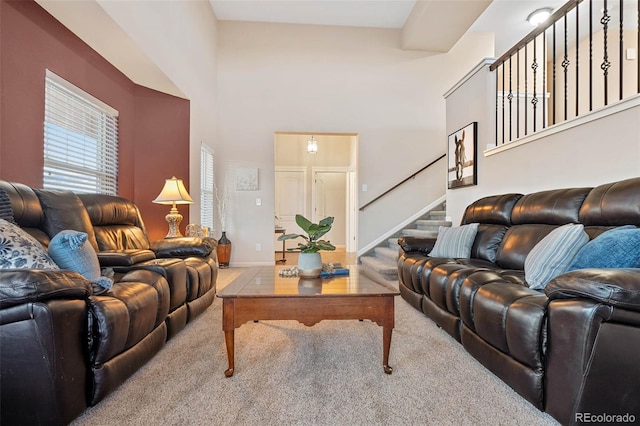 living room with carpet flooring, baseboards, a towering ceiling, and stairs