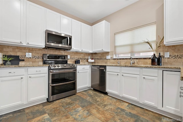 kitchen featuring backsplash, white cabinets, stainless steel appliances, and stone finish flooring