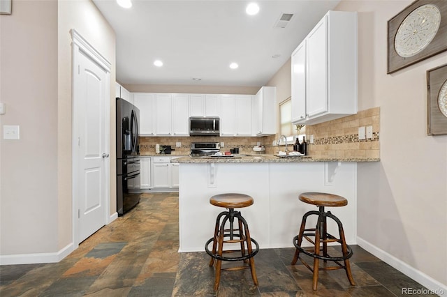 kitchen featuring visible vents, backsplash, appliances with stainless steel finishes, a peninsula, and white cabinets