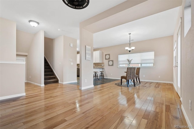 interior space with stairway, baseboards, light wood-style floors, and an inviting chandelier