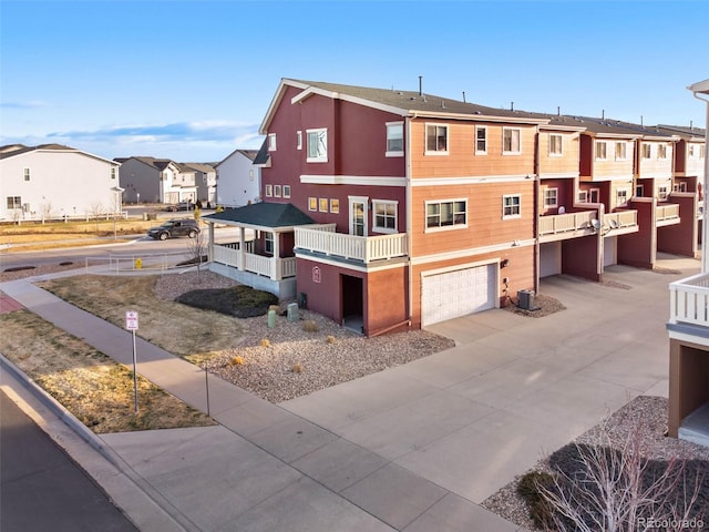 exterior space featuring a garage, a residential view, central AC unit, and driveway