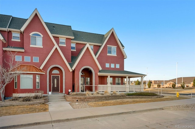 view of front of property featuring a shingled roof, covered porch, and stucco siding