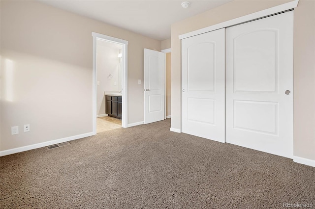 unfurnished bedroom with visible vents, baseboards, light carpet, ensuite bathroom, and a closet