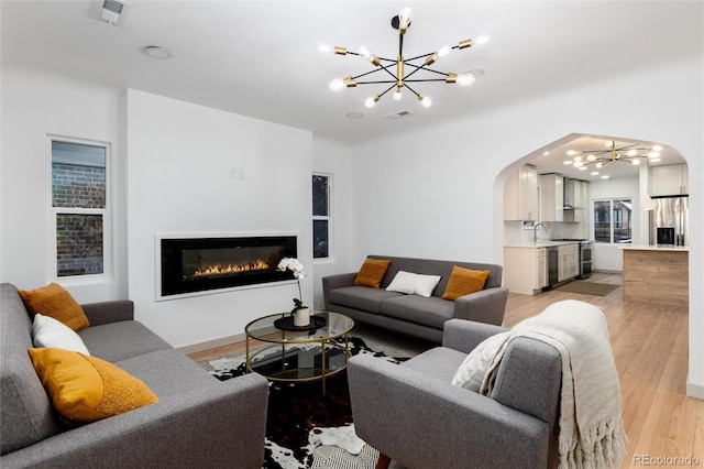 living room with sink, a notable chandelier, and light hardwood / wood-style floors