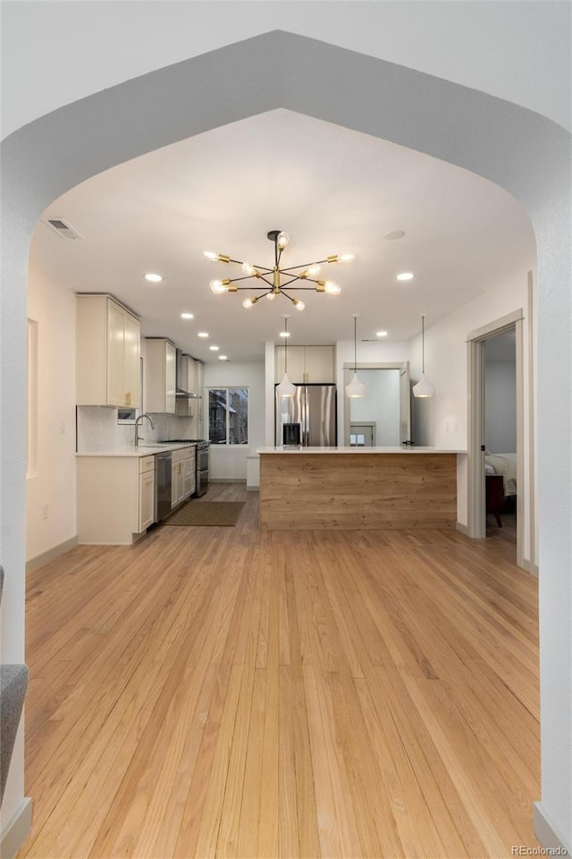 unfurnished living room with a notable chandelier and light hardwood / wood-style flooring