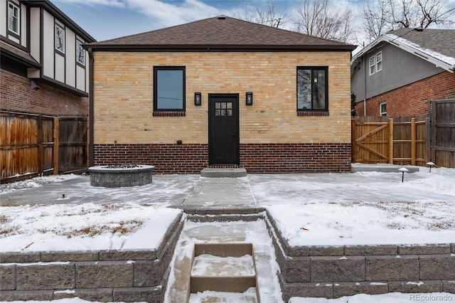 snow covered rear of property featuring an outdoor fire pit