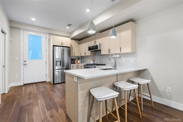 kitchen with appliances with stainless steel finishes, kitchen peninsula, sink, and dark hardwood / wood-style floors