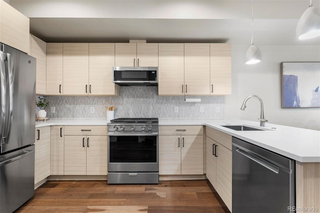 kitchen with sink, stainless steel appliances, hanging light fixtures, and dark hardwood / wood-style flooring