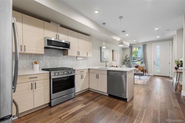 kitchen with stainless steel appliances, sink, dark hardwood / wood-style flooring, kitchen peninsula, and hanging light fixtures