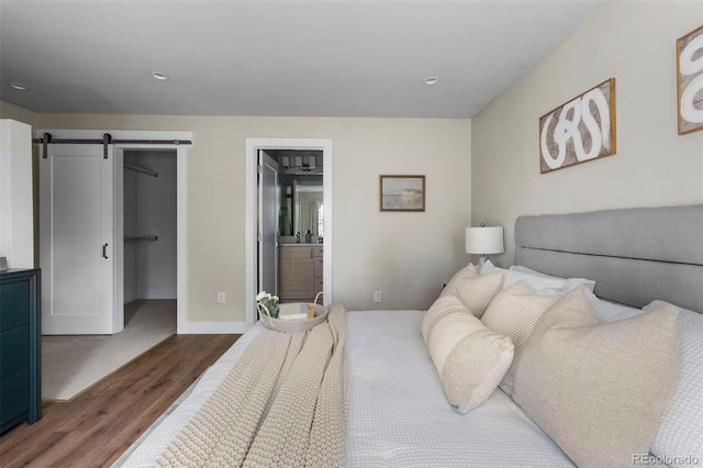 bedroom with a spacious closet, a closet, dark hardwood / wood-style floors, connected bathroom, and a barn door