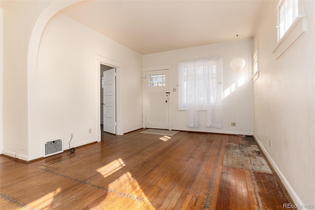 entryway featuring hardwood / wood-style flooring, baseboards, visible vents, and arched walkways