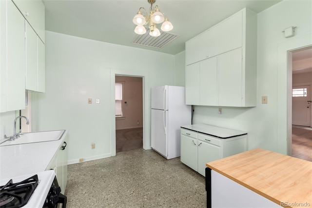 kitchen with visible vents, white cabinets, gas range, freestanding refrigerator, and a sink