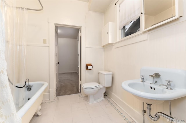 bathroom featuring toilet, a soaking tub, a sink, and tile patterned floors